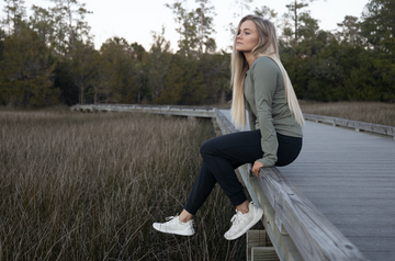 Woman setting on the edge of a salt marsh, a type of wetland